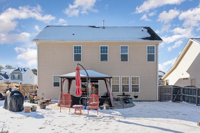 snow covered house featuring fence and a gazebo