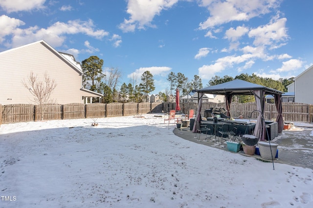 snowy yard with a fenced backyard and a gazebo