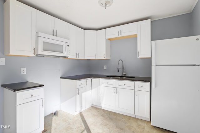 kitchen featuring white appliances, dark countertops, a sink, and white cabinets