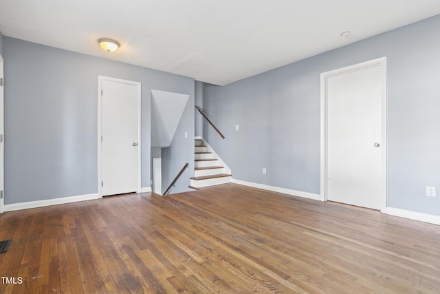 spare room with visible vents, stairs, baseboards, and wood finished floors