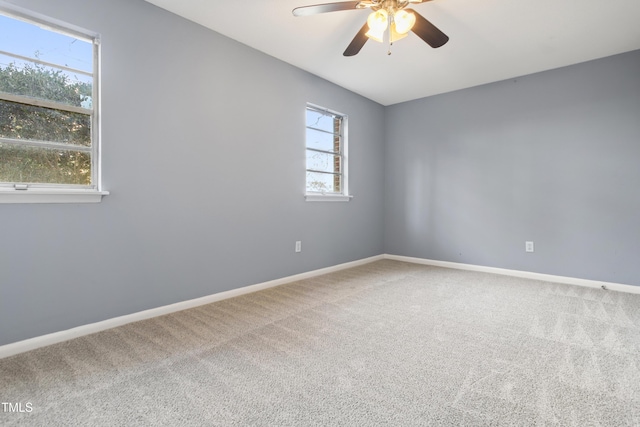 carpeted empty room featuring a ceiling fan and baseboards