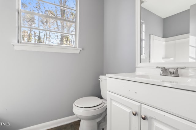 bathroom featuring toilet, baseboards, and vanity