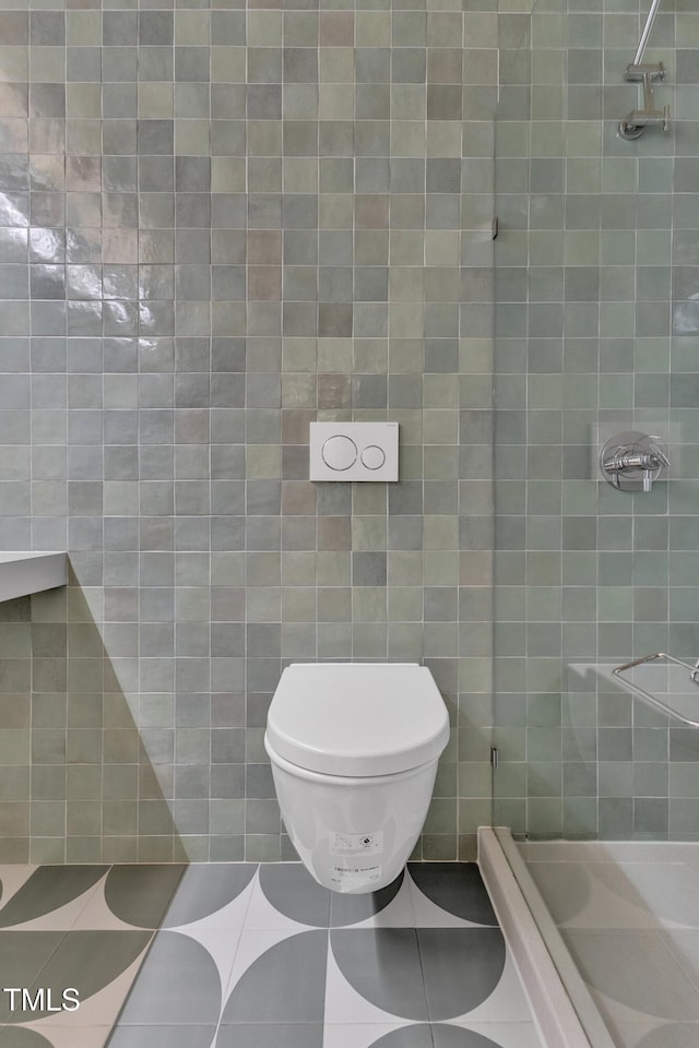 bathroom with a stall shower, toilet, and tile walls