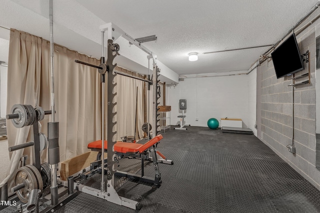 exercise area with concrete block wall and a textured ceiling