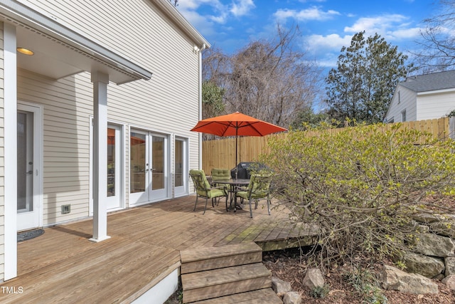 wooden terrace with outdoor dining space, french doors, and fence