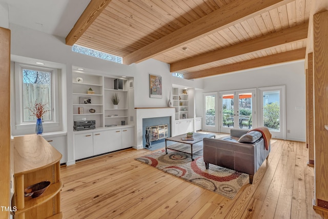 living area featuring light wood-type flooring, a fireplace with flush hearth, beam ceiling, and french doors