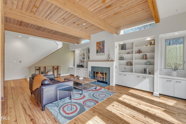 living area featuring a fireplace with flush hearth, wood ceiling, beam ceiling, and light wood finished floors