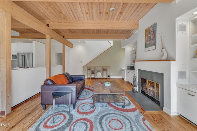 living room featuring a glass covered fireplace, beamed ceiling, wood finished floors, and built in features