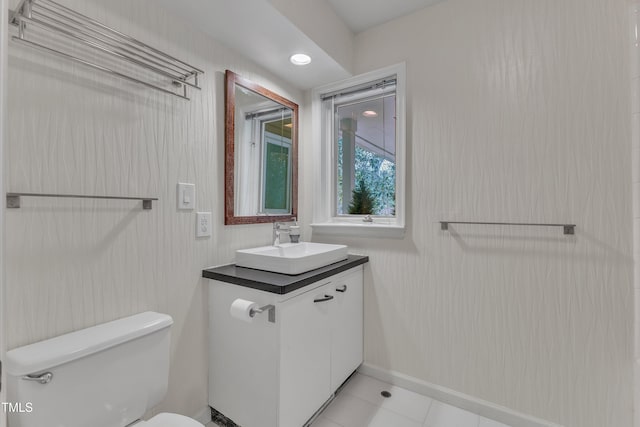 bathroom with toilet, tile patterned floors, baseboards, and vanity