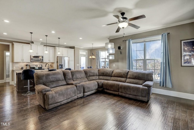 living area with crown molding, dark wood finished floors, recessed lighting, baseboards, and ceiling fan with notable chandelier