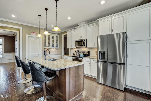 kitchen featuring glass insert cabinets, a sink, white cabinetry, appliances with stainless steel finishes, and a center island with sink