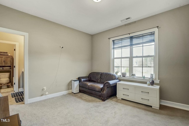 sitting room featuring baseboards, visible vents, and light colored carpet