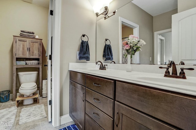 bathroom featuring tile patterned floors, a sink, toilet, and double vanity