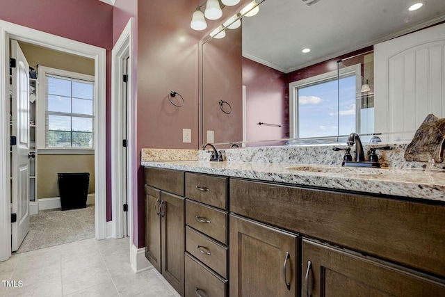 full bathroom featuring baseboards, double vanity, a sink, and tile patterned floors