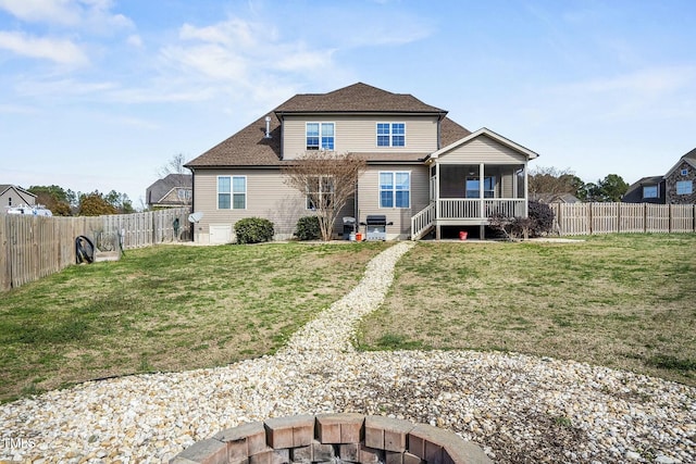 rear view of house with a fire pit, a yard, a fenced backyard, and a sunroom