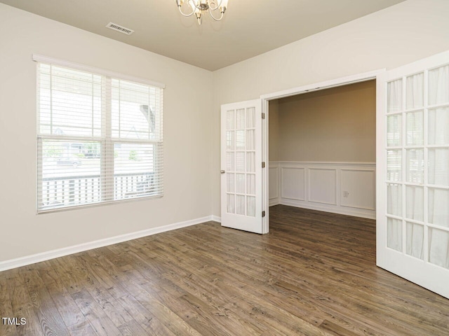 unfurnished room featuring a chandelier, wood finished floors, and baseboards