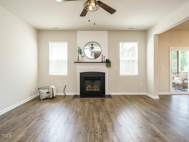 unfurnished living room featuring ceiling fan, a fireplace with flush hearth, dark wood-type flooring, and baseboards