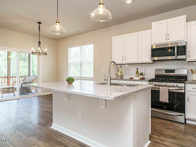 kitchen featuring stainless steel appliances, a sink, backsplash, white cabinets, and recessed lighting