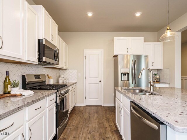 kitchen featuring stainless steel appliances, a sink, white cabinets, light stone countertops, and recessed lighting