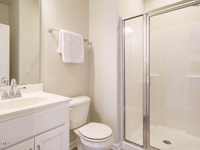 bathroom with a stall shower, toilet, vanity, and baseboards