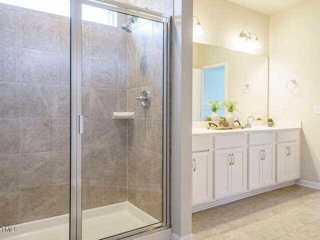 bathroom with a stall shower, tile patterned floors, double vanity, and baseboards