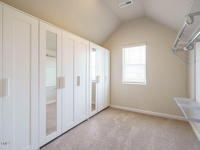 walk in closet with lofted ceiling and light colored carpet