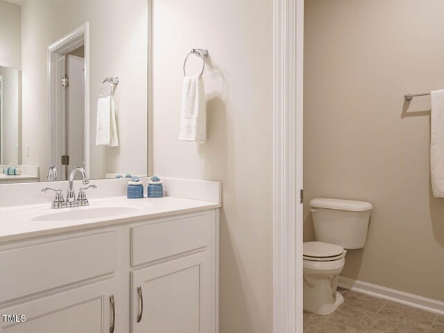 bathroom with toilet, tile patterned flooring, vanity, and baseboards