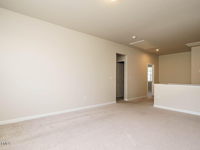 empty room featuring attic access, light carpet, baseboards, and recessed lighting