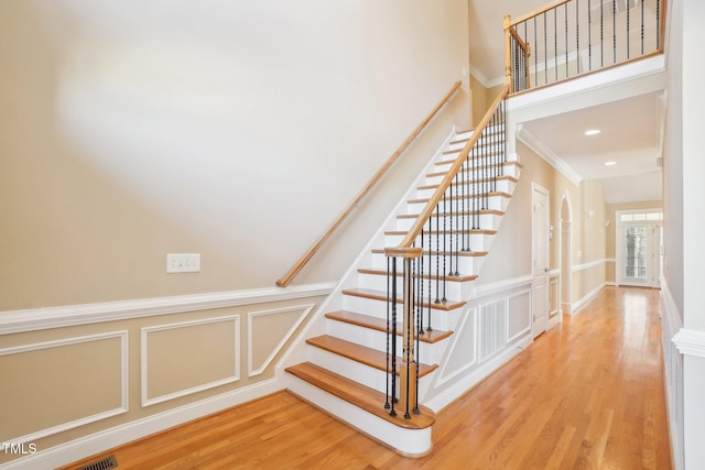 staircase with recessed lighting, wood finished floors, and a decorative wall