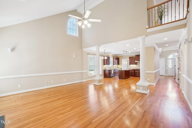 unfurnished living room with ceiling fan, decorative columns, and light wood-style flooring