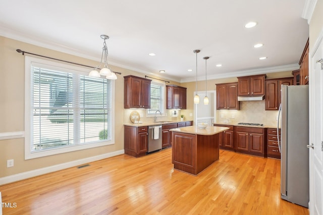 kitchen featuring visible vents, ornamental molding, a sink, under cabinet range hood, and appliances with stainless steel finishes