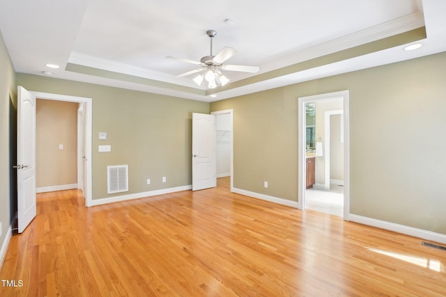 unfurnished bedroom featuring a raised ceiling, visible vents, and light wood-type flooring