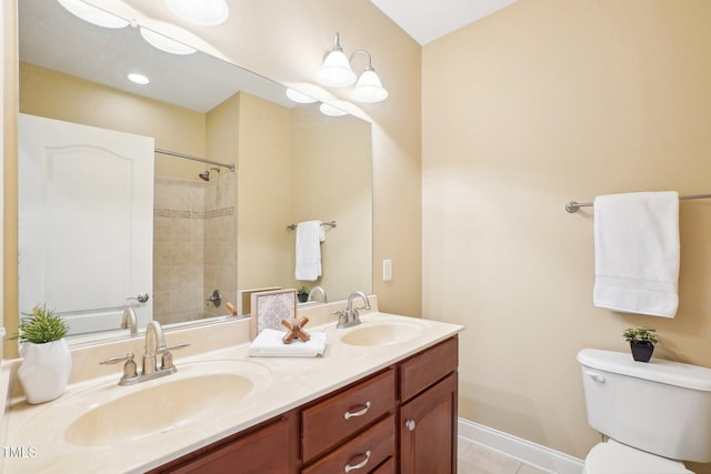 bathroom featuring double vanity, toilet, baseboards, and a sink