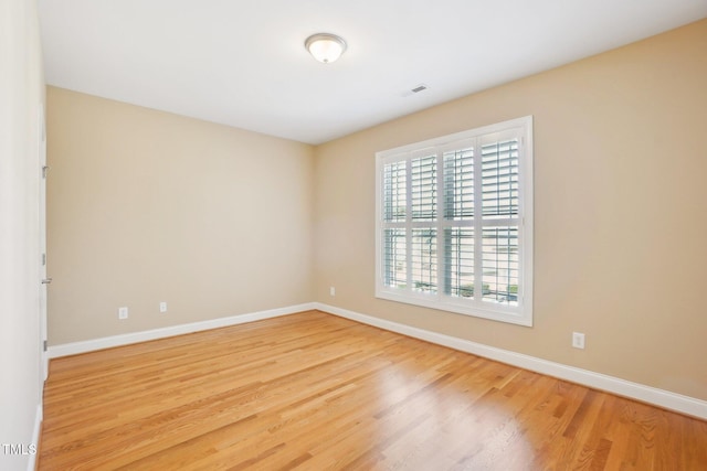 unfurnished room featuring visible vents, baseboards, and wood finished floors