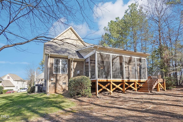 view of front of property featuring central AC, stairway, a front yard, a sunroom, and brick siding