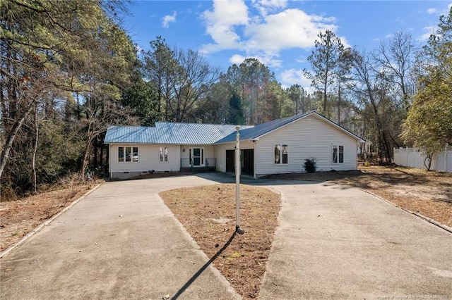 ranch-style house with metal roof, driveway, crawl space, and fence