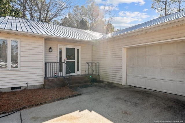 view of exterior entry with crawl space, a standing seam roof, a garage, and metal roof