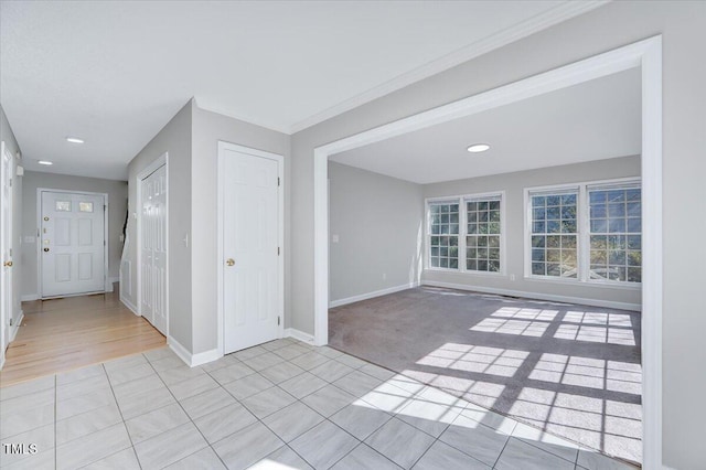 entryway with light carpet, light tile patterned floors, and baseboards