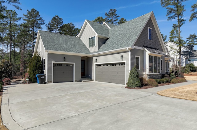 view of side of property with an attached garage, driveway, and roof with shingles