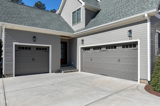 view of front facade with a garage, concrete driveway, and roof with shingles