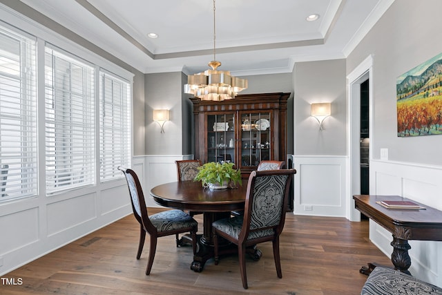 dining area with a chandelier, dark wood-type flooring, wainscoting, and a raised ceiling