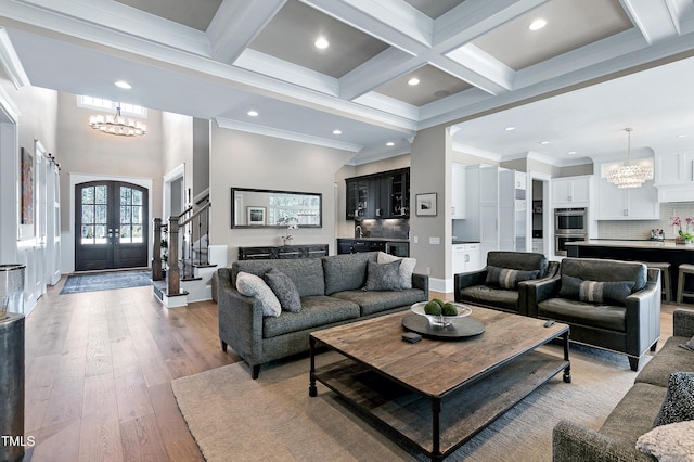 living room featuring french doors, coffered ceiling, beam ceiling, and a notable chandelier