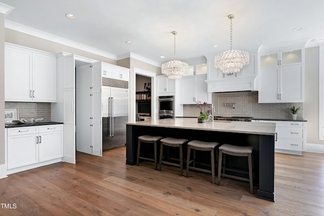 kitchen featuring appliances with stainless steel finishes, white cabinetry, ornamental molding, and wood finished floors