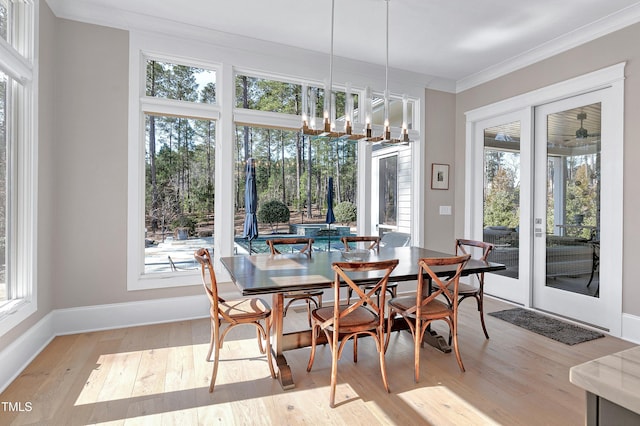 dining area with hardwood / wood-style flooring, baseboards, ornamental molding, and a chandelier