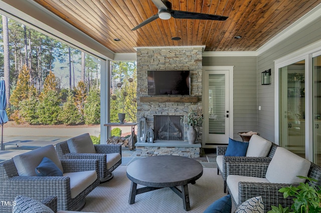 sunroom with ceiling fan, an outdoor stone fireplace, and wooden ceiling