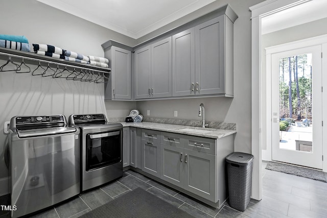 laundry area featuring cabinet space, crown molding, separate washer and dryer, and a sink