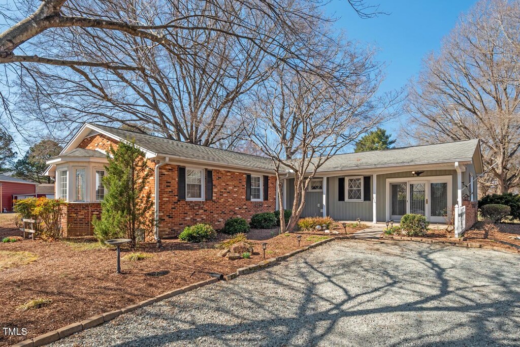 6017 Charlana Dr, Durham, NC 27712 - ranch-style home featuring brick siding, a porch, and gravel driveway