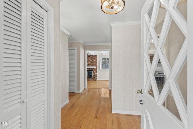 hall with light wood-type flooring, crown molding, and baseboards