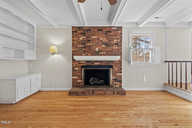 unfurnished living room featuring beam ceiling, a fireplace, and light wood finished floors