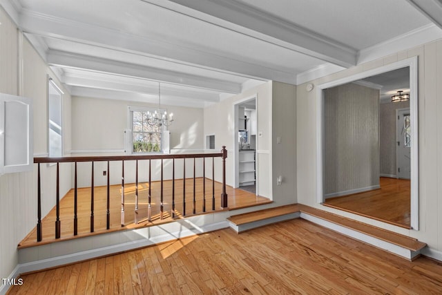 hallway with a notable chandelier, ornamental molding, wood finished floors, beamed ceiling, and baseboards